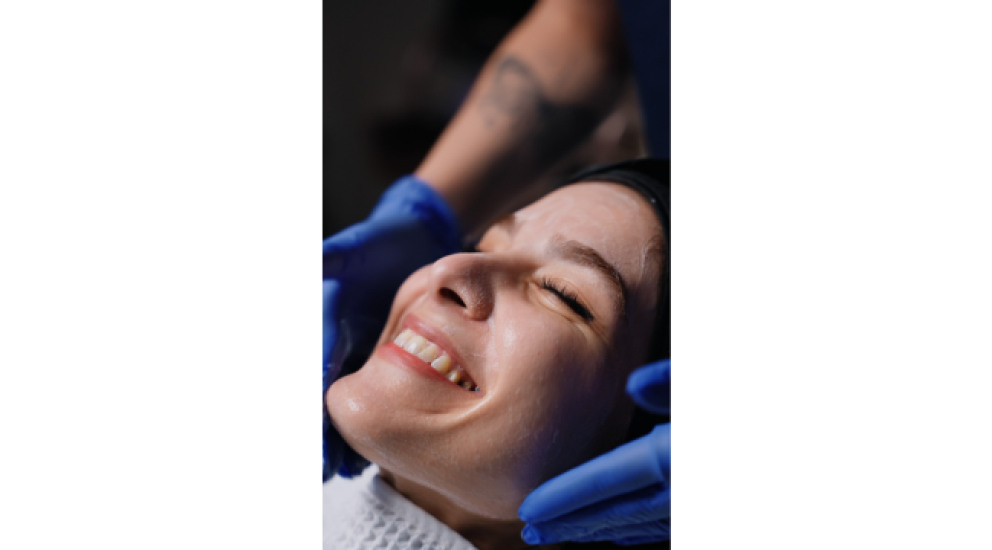 Yalda receiving a relaxing facial treatment and smiling at South Manchester cosmetic dental spa